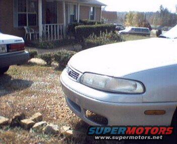 Silver sedan front view. Another car and a limousine are visible