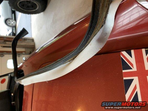 Close-up of a vehicle's door seal and a Union Jack sticker on the body panel. Another vehicle's tire is visible in the background