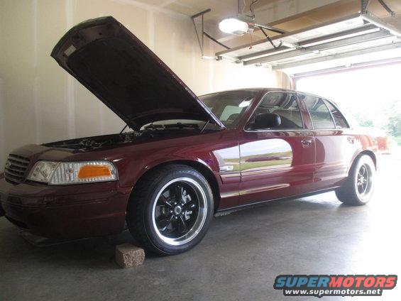 Maroon sedan with hood open, parked in a garage. Aftermarket wheels are visible