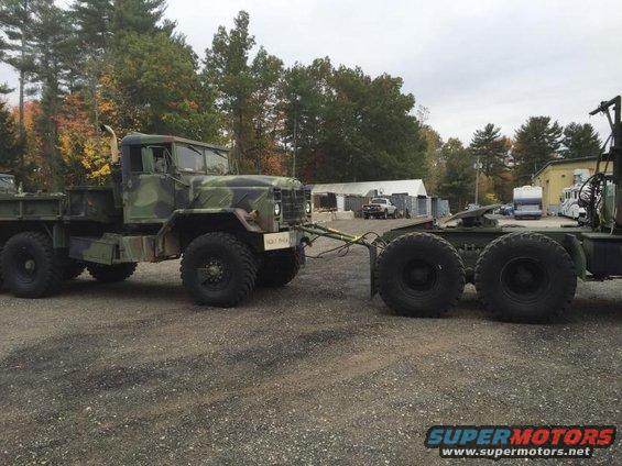 Camouflaged military truck towing a trailer, side view