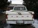 1986 Ford F-150 - The rear of a white Ford pickup truck shows significant rust damage around the tailgate and taillights.