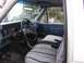 1986 Ford F-150 - The interior of an older model truck is shown, a blue dashboard and seat covers.