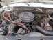 1986 Ford F-150 - The engine bay of a white Ford pickup truck from the 1980s is visible, a V8 engine and associated components.