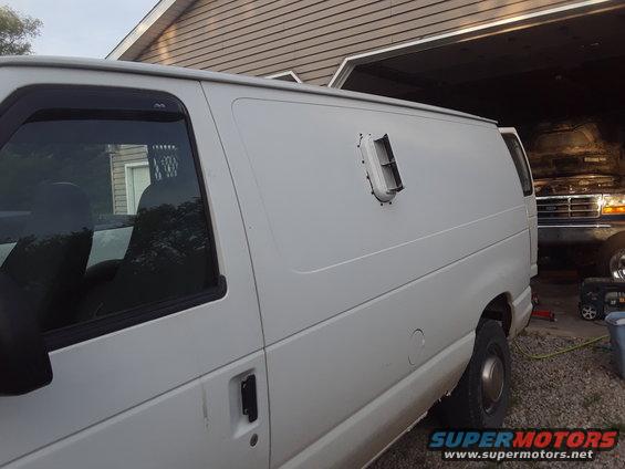 White cargo van side view, parked next to a blue pickup truck