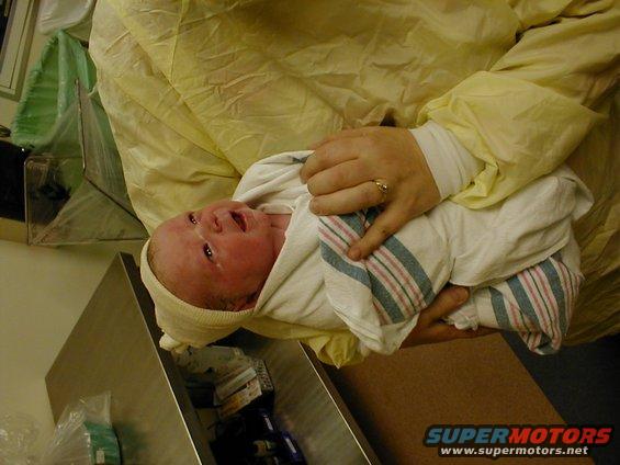 Newborn baby wrapped in a blanket, held by adult hands