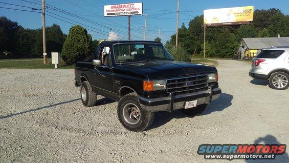 Black pickup truck with a chrome grille and bumper, parked on gravel