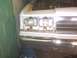 1991 Ford Crown Victoria - The front end of a 1991 Ford Crown Victoria shows its headlights, grille, and exposed engine bay.