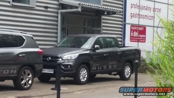 Dark gray SsangYong Musso pickup truck parked next to a dark gray SUV