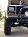 1981 Ford Bronco - Close-up of a white Ford Bronco's front end, showing off-road tires and a bull bar.
