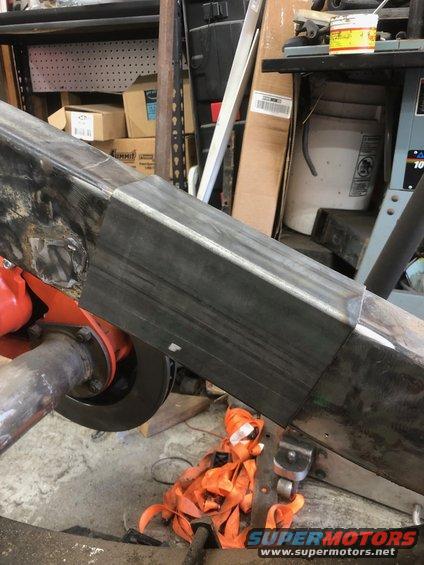 Welded steel frame section with orange straps and a differential visible