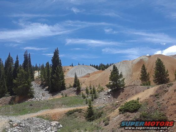 Mining landscape with piles of earth and trees under a blue sky
