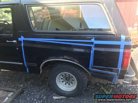 Side view of black 1992 Ford Bronco with blue tape on rear quarter panel
