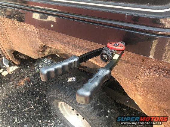 Rivet gun positioned on a rusty fender over a spare tire