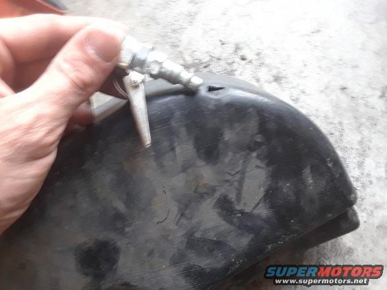 Hand holding silver air chuck to black plastic part with a small opening