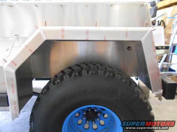 Rear wheel well and tire of a custom vehicle with aluminum paneling