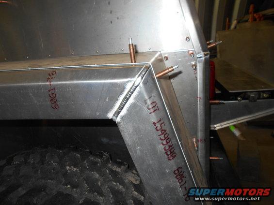 Close-up of a welded aluminum frame section with rivets and a tire visible