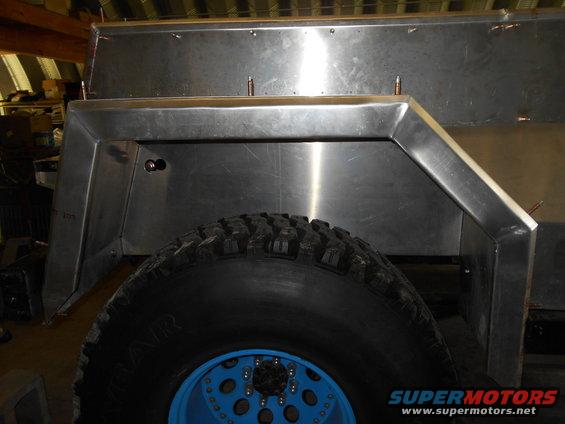 Close-up of a custom metal fender flare and tire on a vehicle, possibly under construction