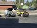 1970 Volkswagen Beetle - Two dune buggies are parked in a lot, one teal and one yellow, with a person attending to the teal vehicle.