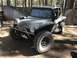 1970 Volkswagen Beetle - A custom dune buggy with a roll cage and off-road tires sits in a dirt lot near a wooden fence.