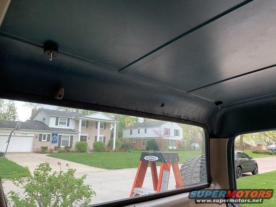 Interior view from a vehicle, looking out at houses and a ladder