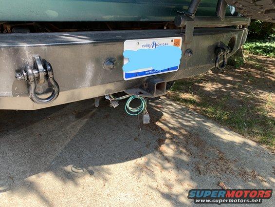 Rear bumper of a 1996 Ford Bronco with a tow hitch, wiring, and a Michigan license plate