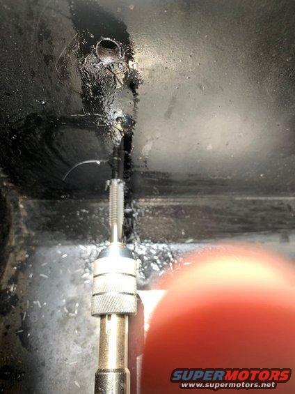 tap wrench threading a hole, metal shavings visible