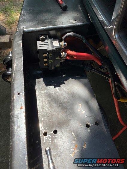 Close-up of a black electrical relay with red wires connected, mounted in a metal compartment