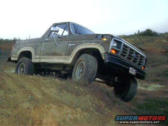 Brown Ford Bronco with white trim stuck in mud, front 3/4 view