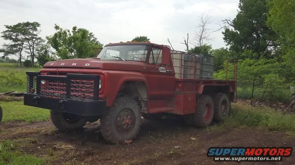 Red flatbed truck with a large grille guard and tanks in the bed