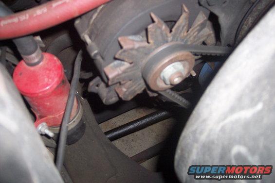 close-up of car alternator with belt and red fluid canister