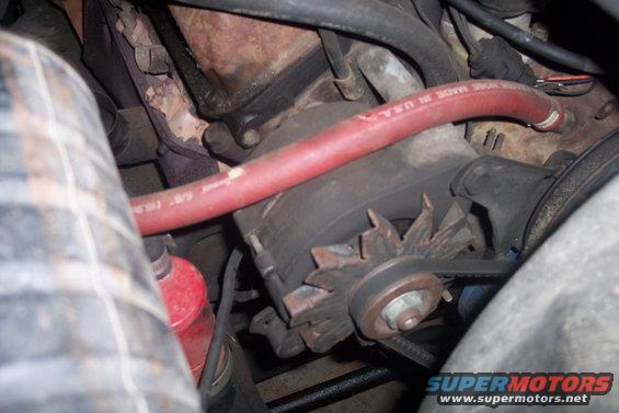 Alternator with fan and belt, red hose, and red fluid reservoir