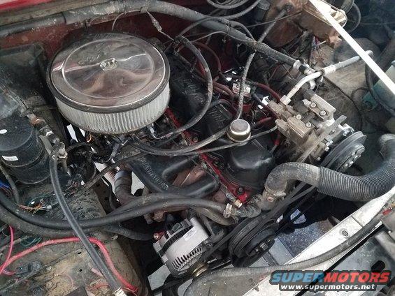 Engine bay with air filter, alternator, and AC compressor visible