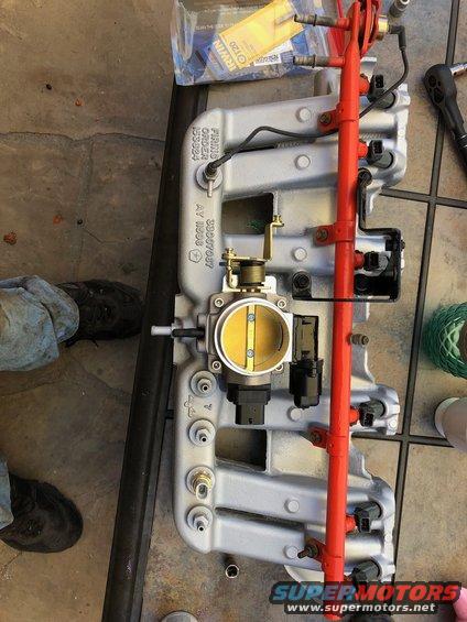 Engine intake manifold assembly with throttle body, fuel rail, and injectors. Part numbers visible