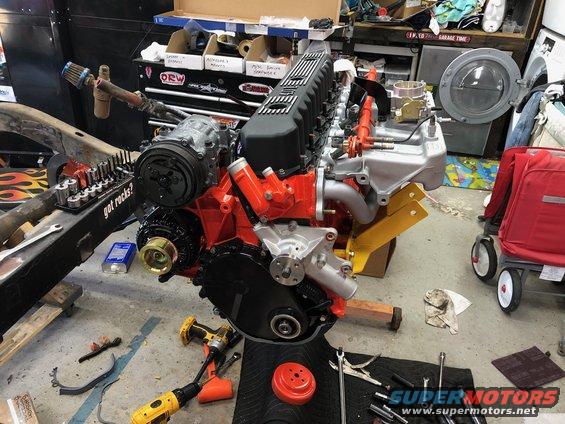 Engine assembly on a stand with tools around it. Some parts are orange and black