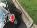 2008 Ford Focus - Rear view of a damaged black car with a detached hubcap, parked next to a curb.