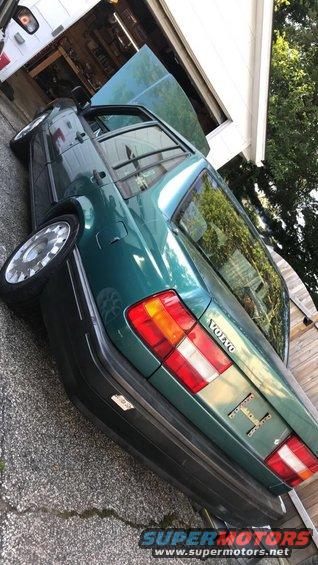 Green 1994 Volvo 940 sedan, rear 3/4 view, hood open, parked in driveway