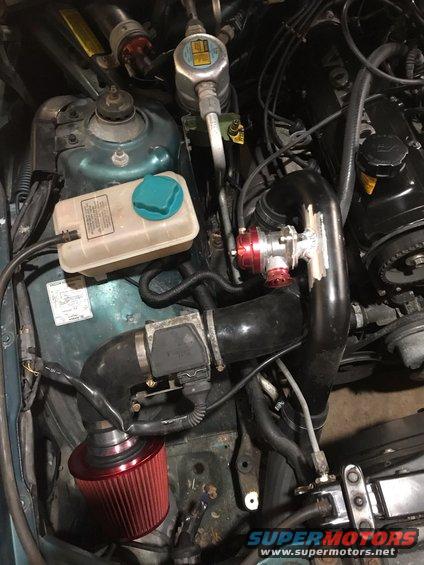 Engine bay showing aftermarket turbo piping, blow-off valve, and air filter