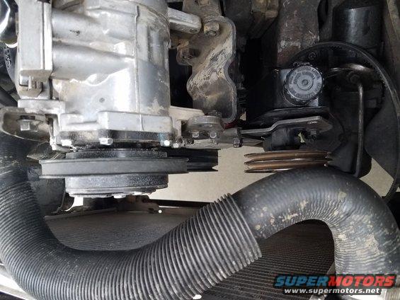 Engine pulleys, belts, and hoses visible near a radiator