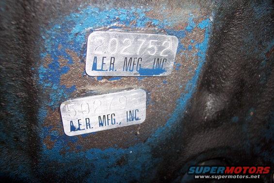 Two metal tags with numbers and 'AER. MFG. INC.' text on a blue and black painted surface
