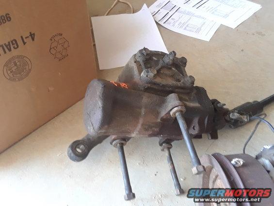 Differential housing with bolts and driveshaft attached, next to a cardboard box
