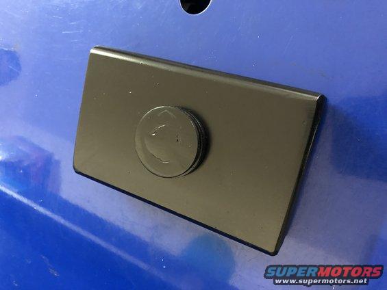 Black metal plate with circular emblem on blue surface
