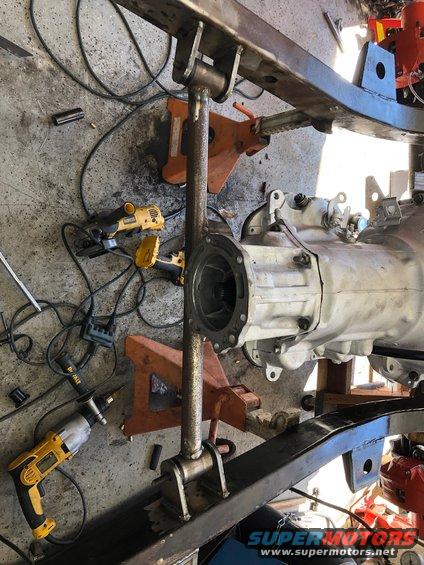 close-up of vehicle transmission and frame parts on jack stands with tools