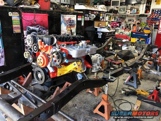 Engine and chassis on jack stands in a cluttered garage