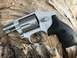 1993 Ford Bronco - A close-up view of a silver revolver with a black grip, set against a textured wooden background. Markings indicate it is chambered for .38…