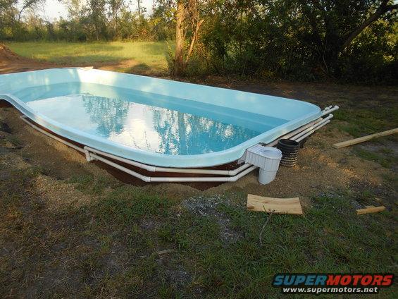 Above-ground swimming pool with plumbing and skimmer, surrounded by dirt and grass