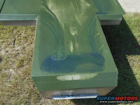 green metal box with rivets and some dark stains on top