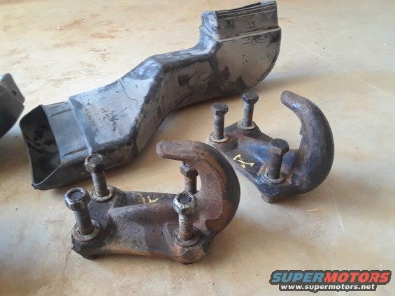 Two rusty tow hooks and a black plastic air intake duct