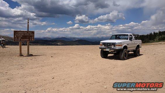 White Ford Bronco parked on a dirt road with mountains in the background