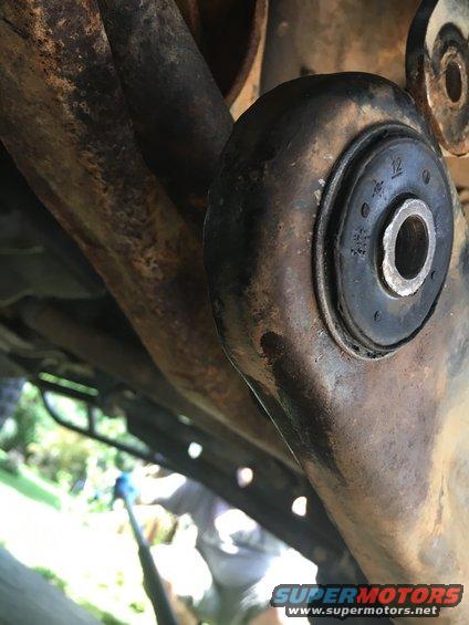Close-up of rusty vehicle suspension parts with a rubber bushing marked '12'