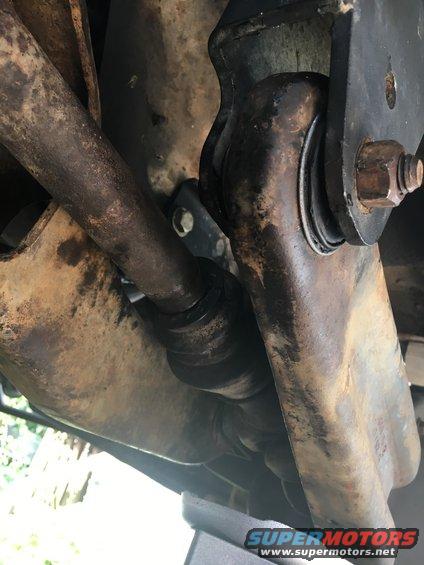 Close-up of rusty suspension components and a black rubber bushing